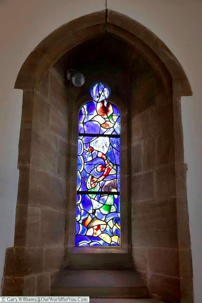 A striking stained glass window by Marc Chagall in Tudeley Church depicts a tumbling red angel surrounded by abstract forms and vibrant colours. The expressive design adds to the church’s reputation as one of the most unique places to visit in Kent.