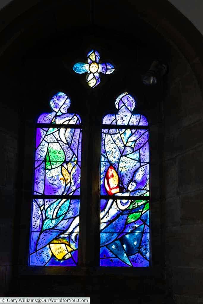 A serene angel is portrayed in soft blue and purple hues in this Marc Chagall stained glass window at All Saints’ Church, Tudeley. The peaceful imagery enhances the spiritual atmosphere of this historic Kent church.