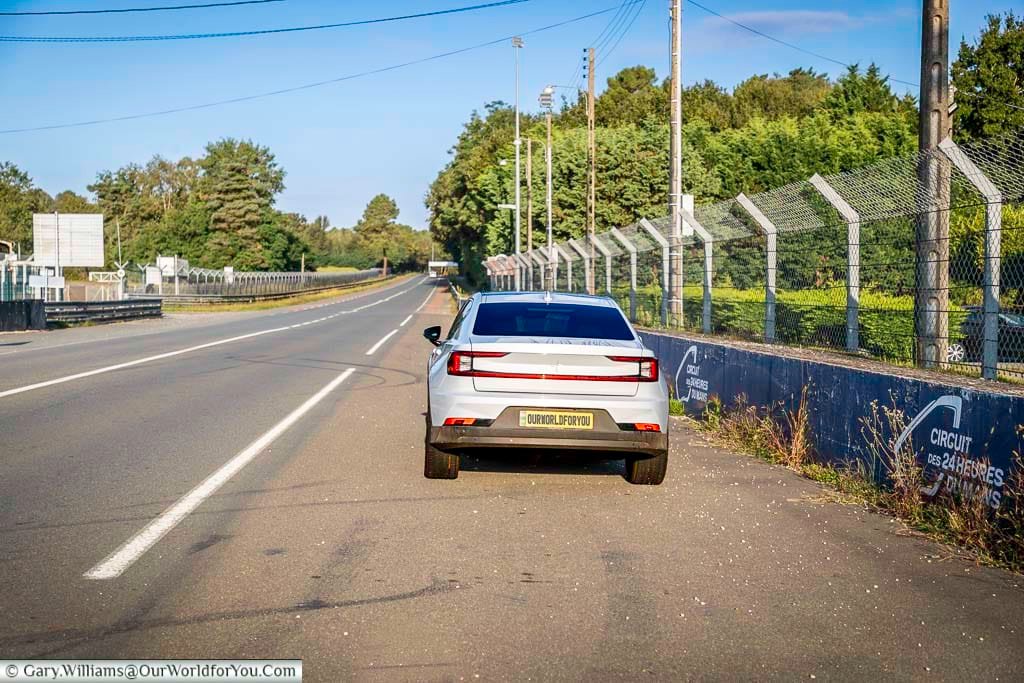 A sleek Polestar car is parked alongside the famous Circuit des 24 Heures du Mans race track in France. This iconic location is synonymous with motorsport history and attracts visitors from around the world.