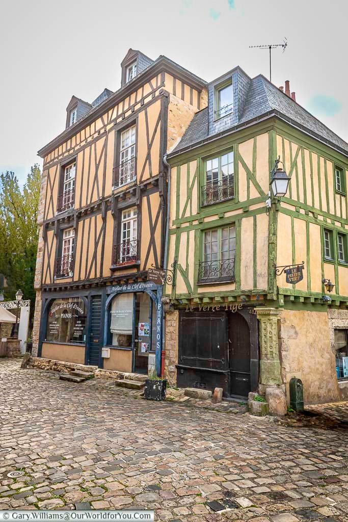 A distinctive green timber-framed building stands at a corner in the historic streets of Le Mans. Surrounded by cobbled roads and old architecture, it highlights the unique character of this French medieval city.