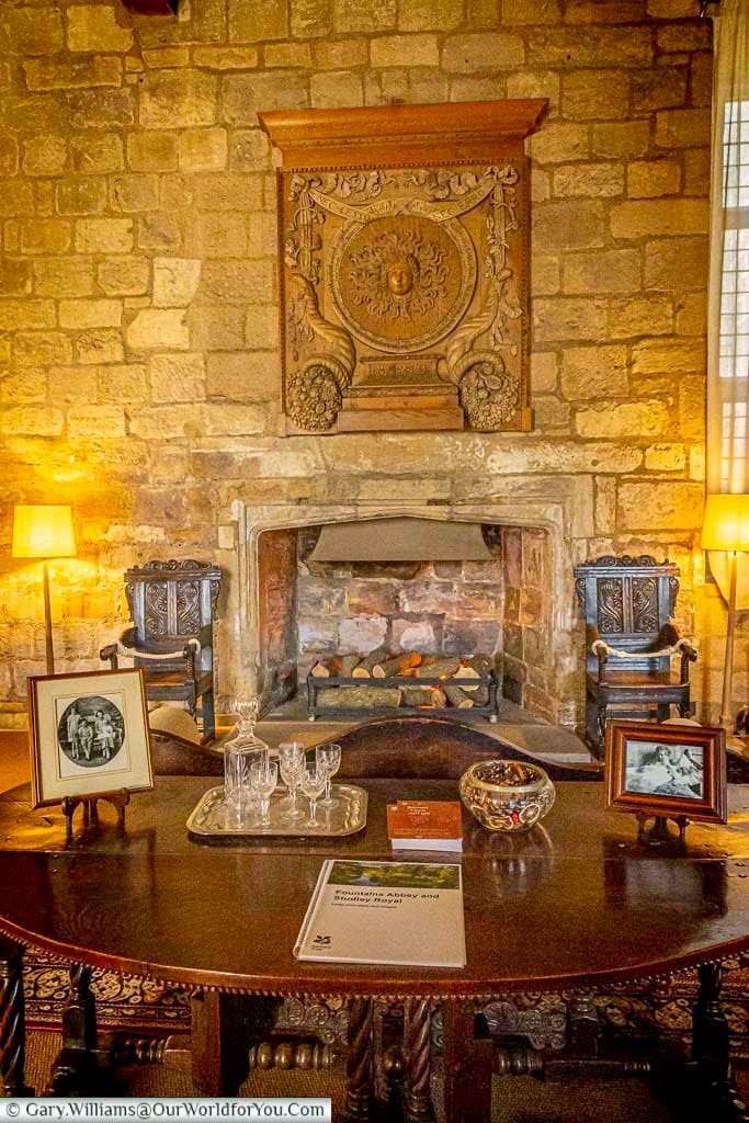 Warm and inviting interior of Fountains Hall in Yorkshire, featuring a traditional stone fireplace, antique furniture and historic décor. The beautifully preserved manor house offers visitors a glimpse into centuries of Yorkshire history at this popular National Trust property.