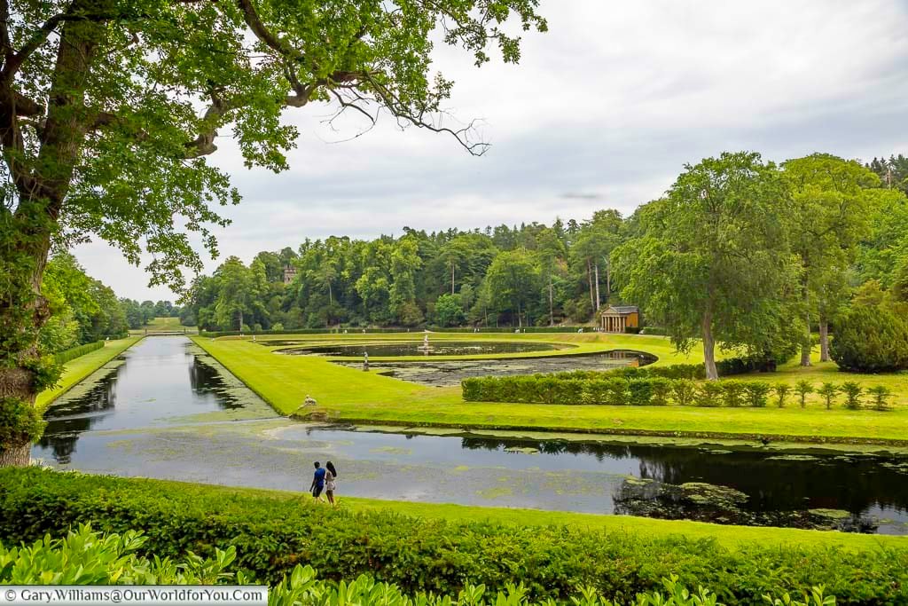Lush green landscape at Studley Royal Water Garden in Yorkshire, with sweeping canals, curved ponds and the Temple of Piety framed by mature woodland. This peaceful National Trust garden near Fountains Abbey is one of the most beautiful hidden gems and historic places to visit in Yorkshire.
