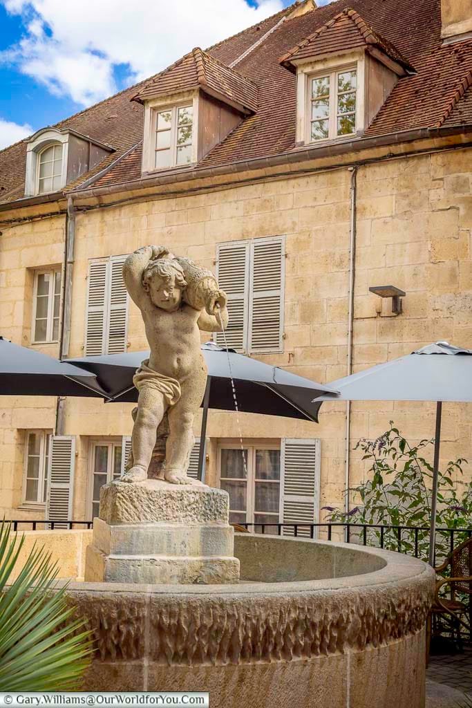 The elegant Fontaine à l'Enfant features a classical stone sculpture at the centre of a charming courtyard surrounded by historic buildings. This attractive fountain is a peaceful landmark and a delightful stop on a walking tour through the old town of Dole.