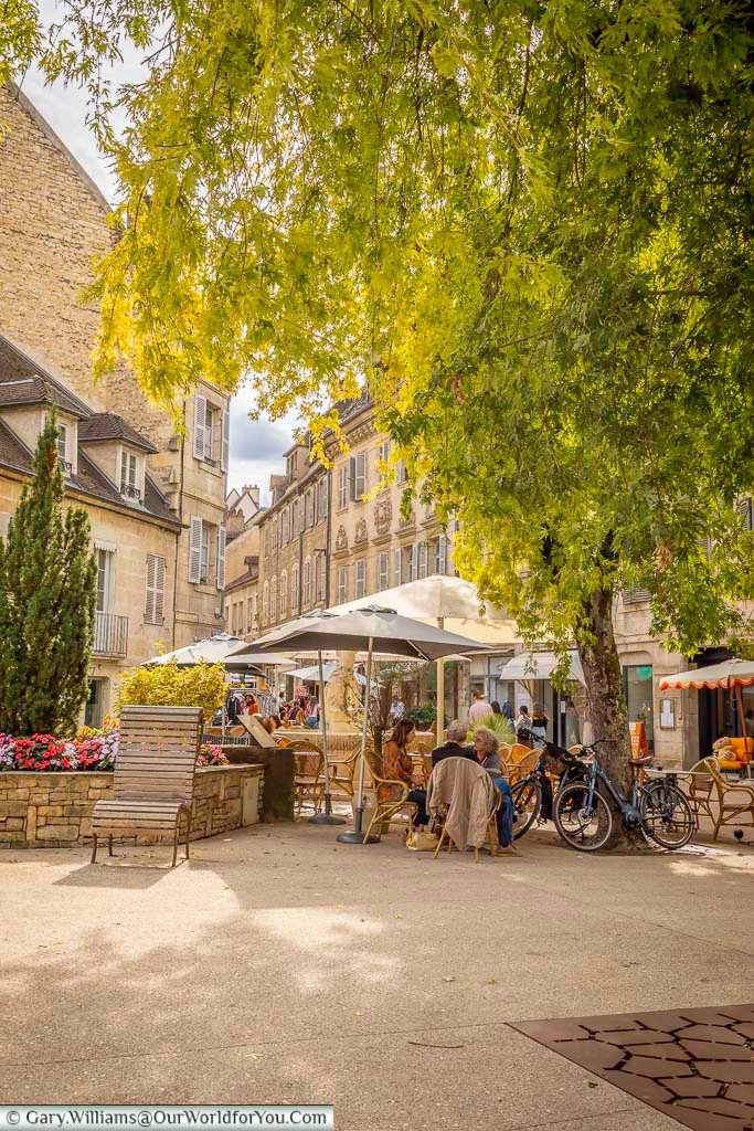 Visitors relax beneath leafy trees at Place aux Fleurs, a charming square in the heart of Dole surrounded by cafés and elegant historic buildings. This peaceful setting captures the atmosphere of one of the Jura region’s most picturesque towns and hidden gems.