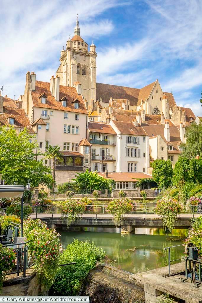The picturesque Canal des Tanneurs is lined with colourful flower displays, leading the eye towards the impressive Collégiale Notre-Dame de Dole. This scenic riverside view showcases the charm of Dole and is one of the town’s most iconic attractions in the Jura region.