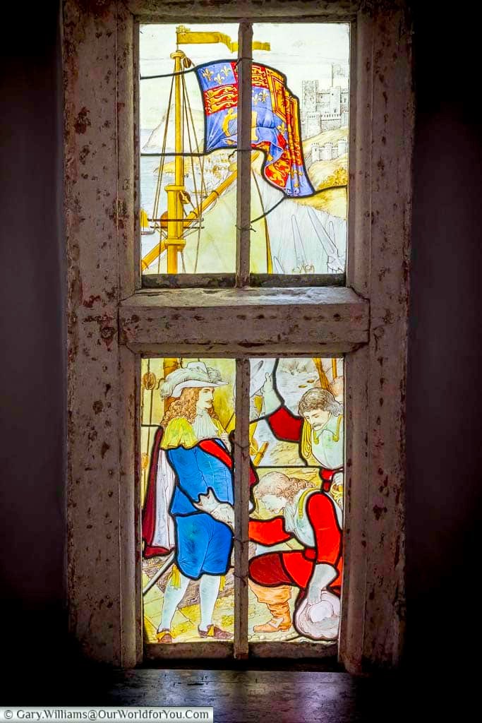 Historic stained-glass window at Restoration House in Rochester, Kent, depicting a colourful maritime scene with figures and a sailing ship.