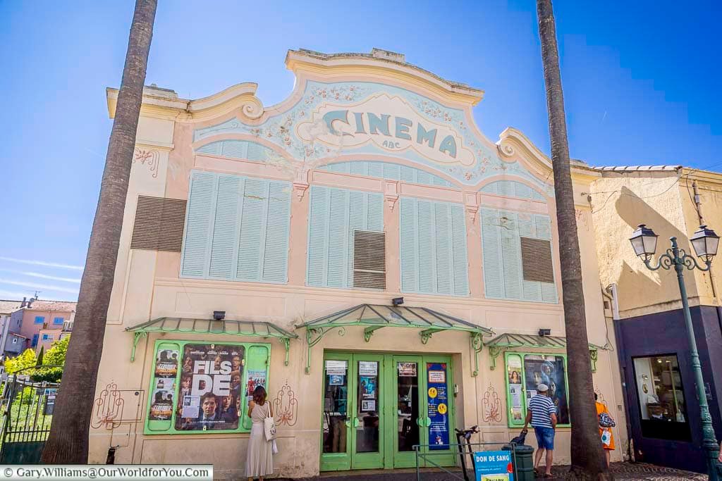 The charming pastel Art Deco-style façade of Cinéma ABC in the centre of Sanary-sur-Mer, framed by tall palm trees.