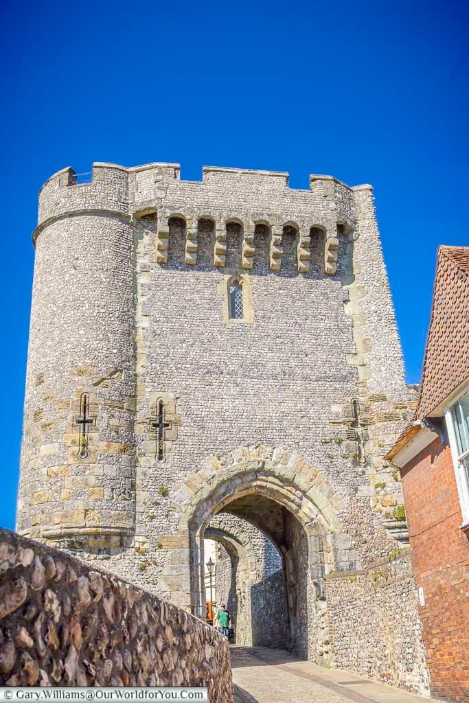 The imposing medieval Barbican at Lewes Castle, its flint walls, rounded tower and arched gateway standing beneath a vivid blue East Sussex sky.