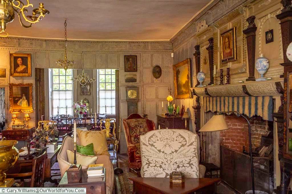 A wider view through the richly furnished Oak Saloon at Restoration House in Rochester, filled with historic paintings, antique furniture and decorative features.