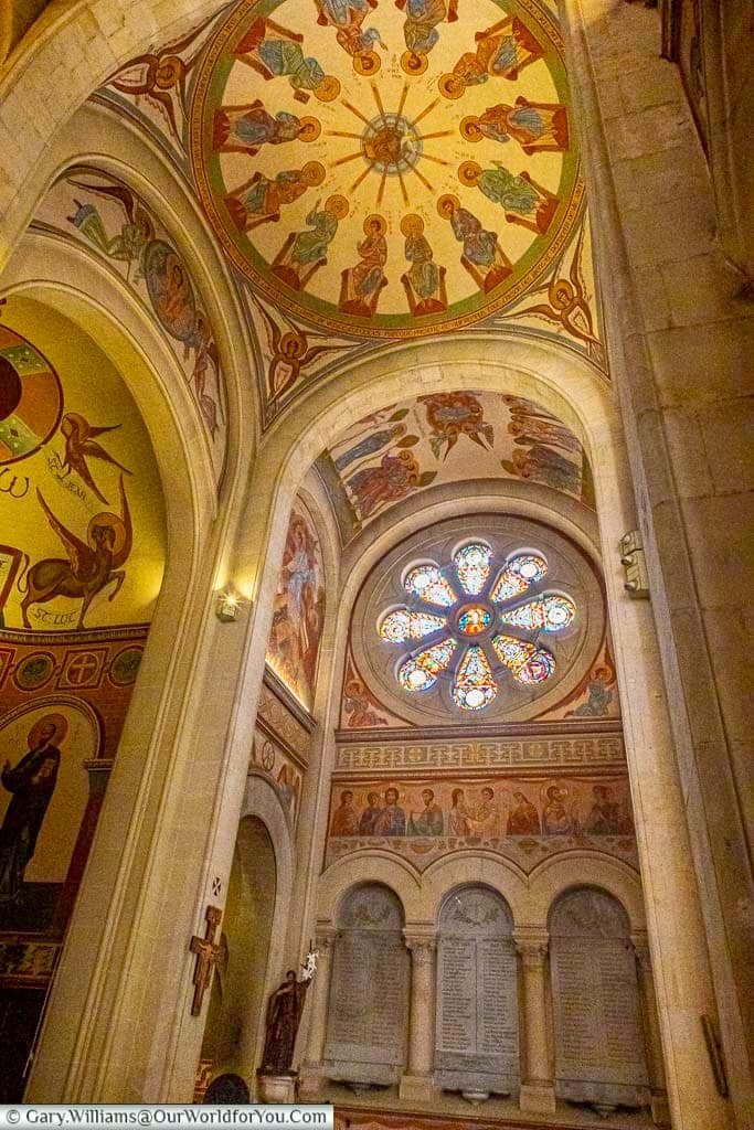 Colourful ceiling frescoes, stone arches and a stained-glass rose window inside the richly decorated Saint-Nazaire Church in Sanary-sur-Mer.