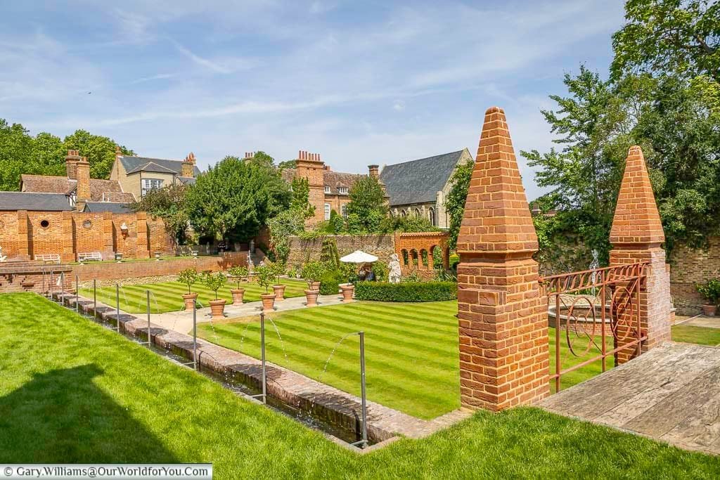 Beautifully symmetrical formal gardens at Restoration House in Rochester, with manicured lawns, fountains, terracotta pots and distinctive historic brick architecture.