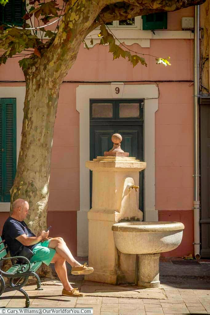 A traditional stone drinking fountain beneath a shady plane tree in Sanary-sur-Mer, creating a peaceful corner of the historic town centre.