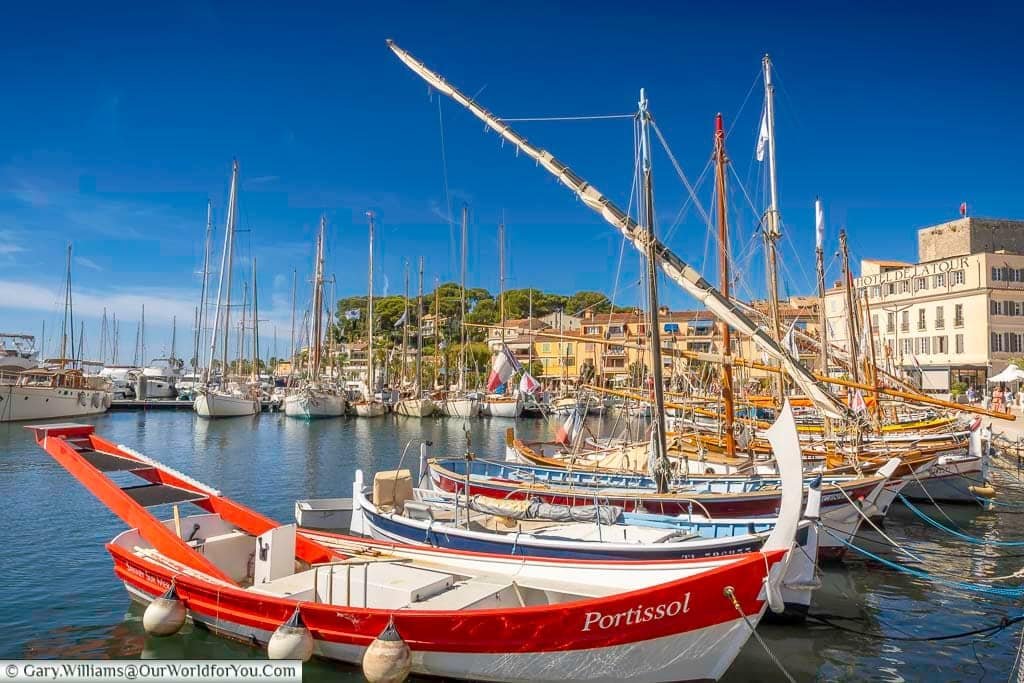 Colourful traditional Provençal pointu fishing boats moored in the historic harbour at Sanary-sur-Mer beneath a brilliant Mediterranean sky.