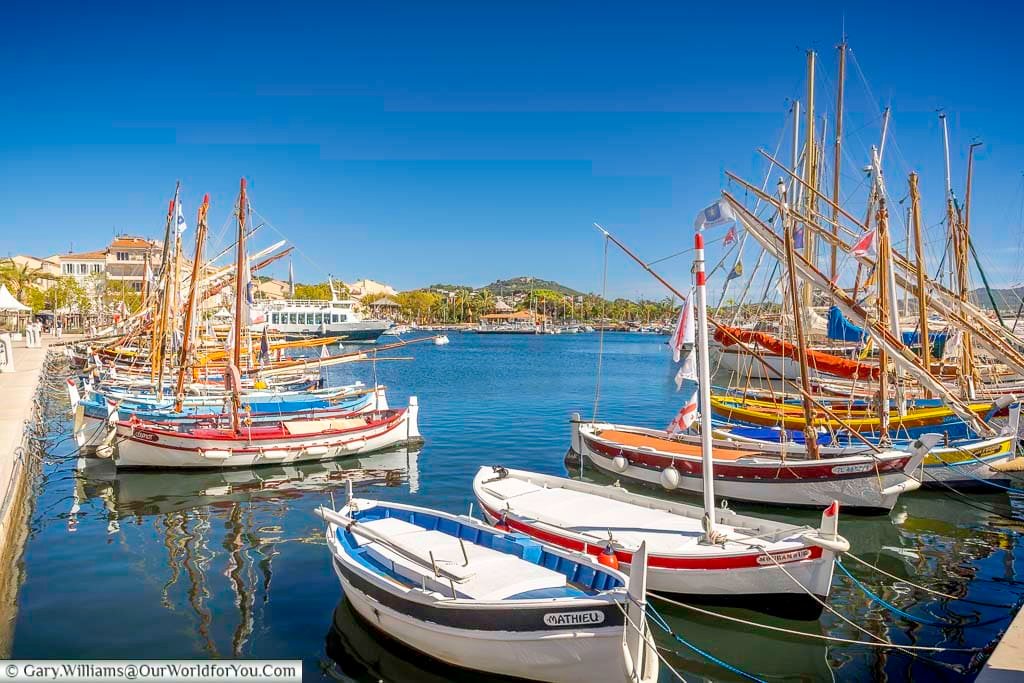 A colourful collection of traditional wooden fishing boats filling the picturesque harbour at Sanary-sur-Mer on a bright sunny day.