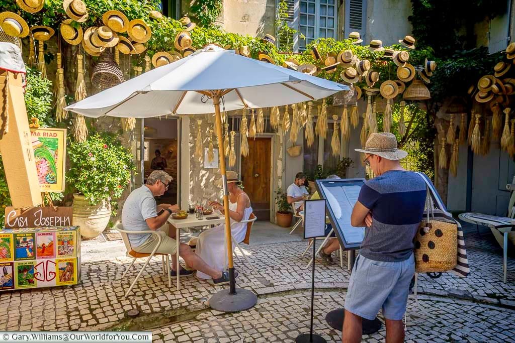 Charming café courtyard surrounded by traditional straw hats in the historic centre of Saint-Rémy-de-Provence, Provence, France.