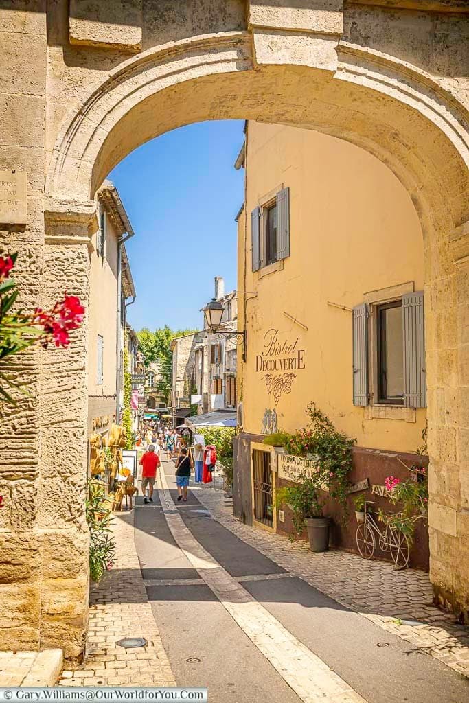 View through the historic Porte Saint-Paul towards a lively street in the old town of Saint-Rémy-de-Provence, Provence.