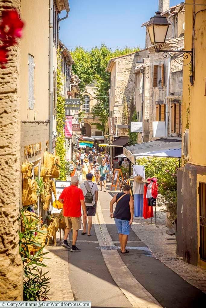 Visitors strolling along Rue de la Commune, a picturesque shopping street lined with stone buildings in Saint-Rémy-de-Provence.