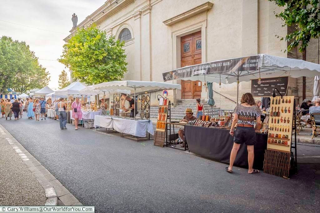 Artisan stalls lining the street beside the church during the lively summer night market in Saint-Rémy-de-Provence, Provence.