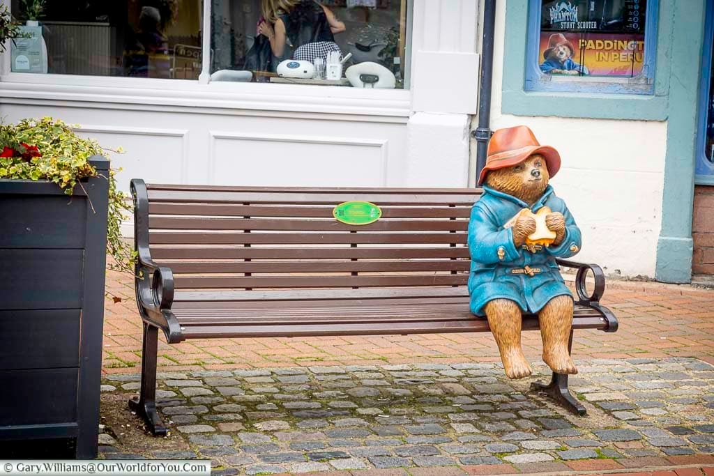 A colourful Paddington Bear statue sits on a wooden bench in Penrith town centre, wearing his familiar blue coat and red hat. This delightful attraction provides a fun photo opportunity for visitors exploring the historic Cumbrian market town.